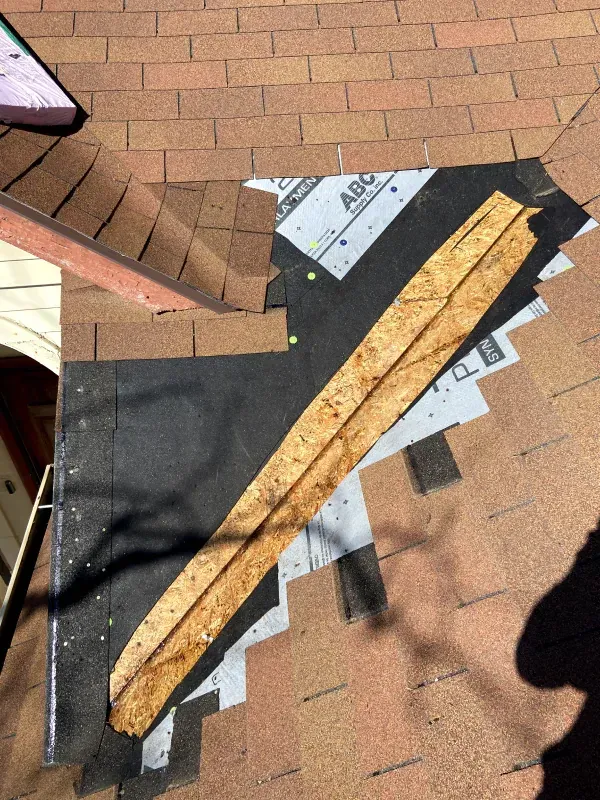 A piece of wood is laying on top of a brick roof.