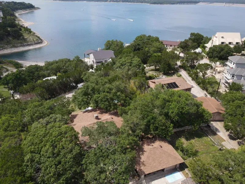 An aerial view of a house surrounded by trees and a lake