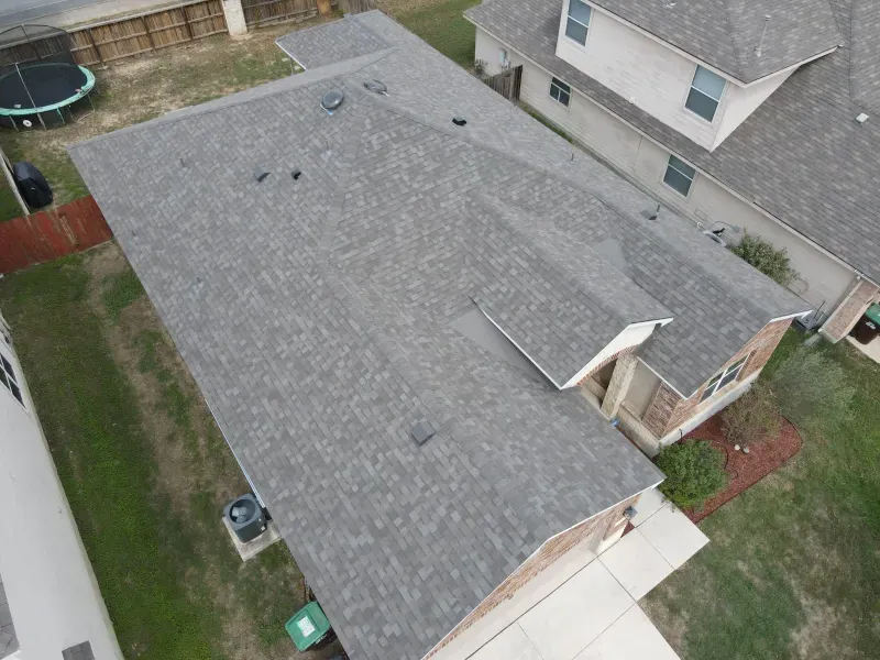 An aerial view of a roof of a house with a trampoline in the backyard.