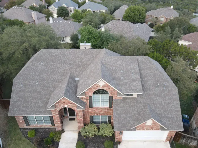 An aerial view of a large brick house with a gray roof