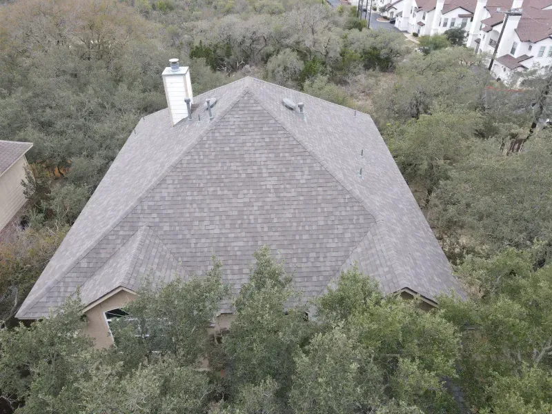 An aerial view of a house with a pyramid shaped roof surrounded by trees.