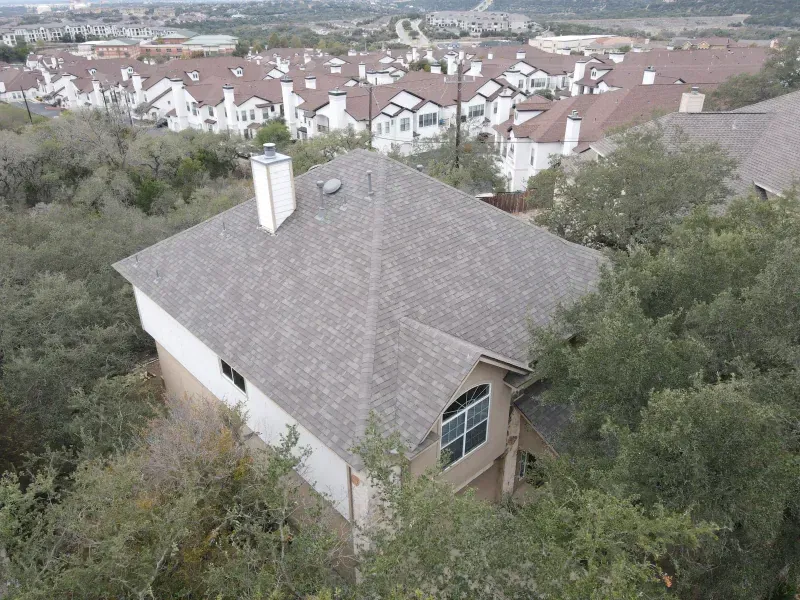 An aerial view of a house with a roof that is surrounded by trees