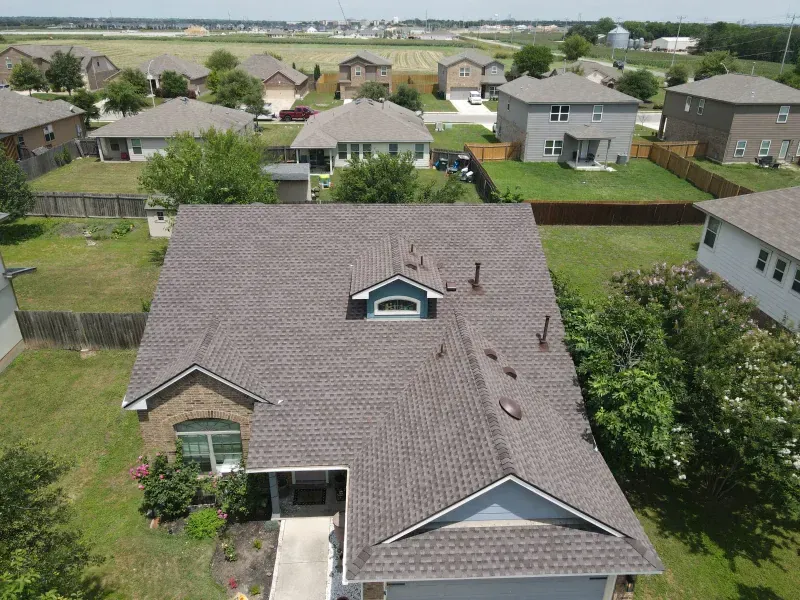 An aerial view of a house with a roof in a residential area.