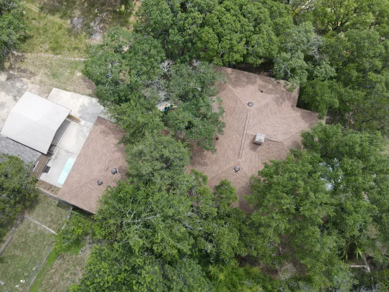 An aerial view of a house surrounded by trees and grass.