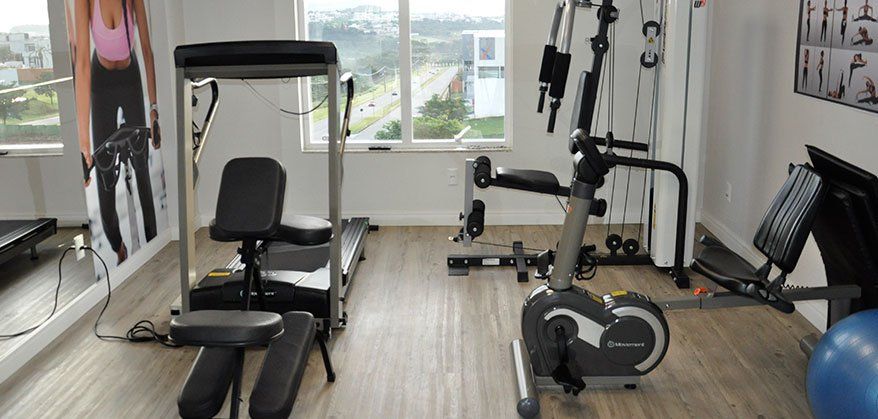 Uma academia com esteira, bicicleta ergométrica e uma bola de pilates.