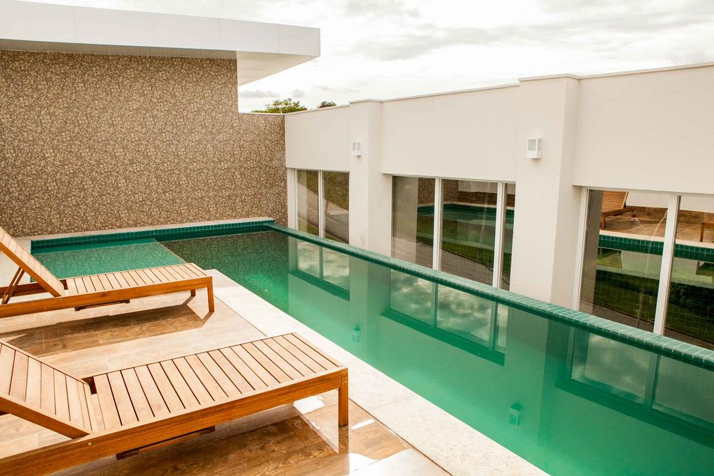 Uma grande piscina com duas espreguiçadeiras de madeira ao lado.