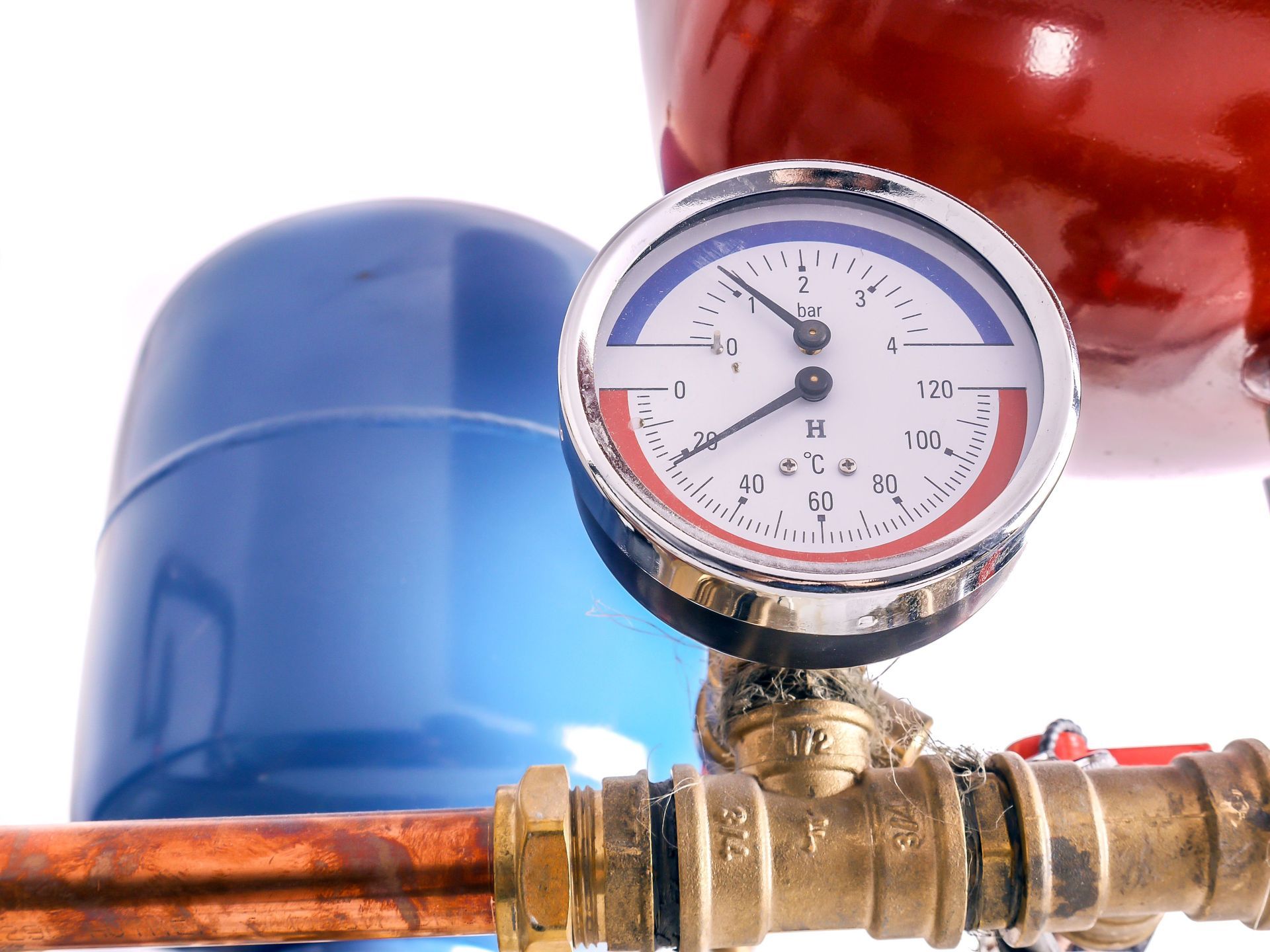 Pressure gauge on a brass pipe with blue and red tanks in the background Pressure gauge on a brass pipe with blue and red tanks in the background