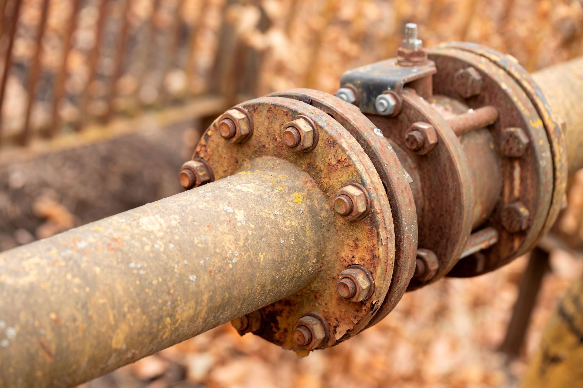 Rusty industrial pipe flange with bolts, showing a corroded metal connection outdoors