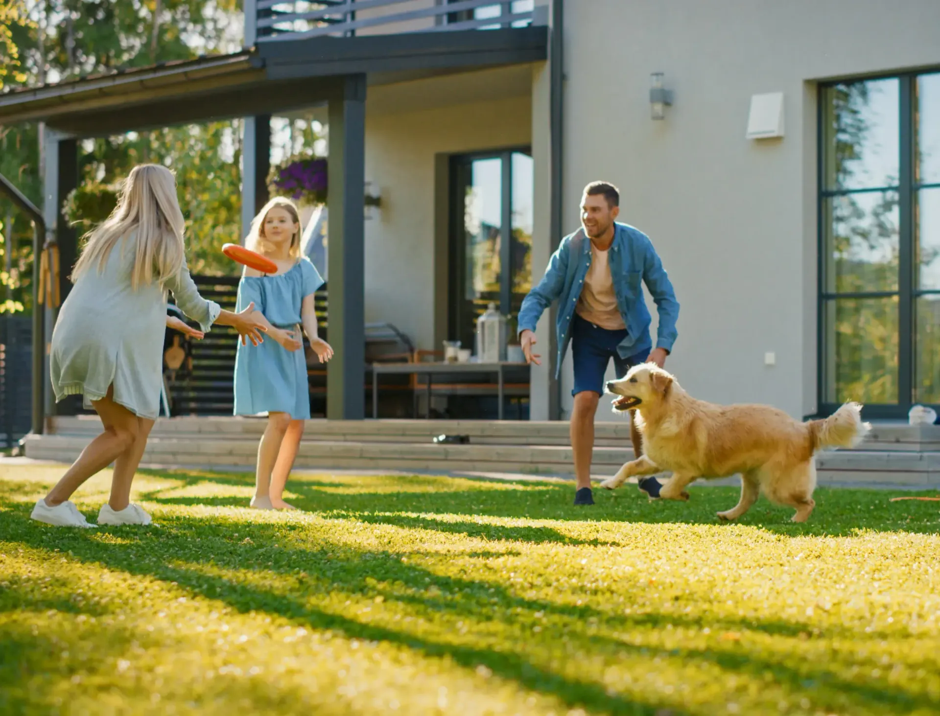 A sprinkler is spraying water on a lush green lawn in front of a house.