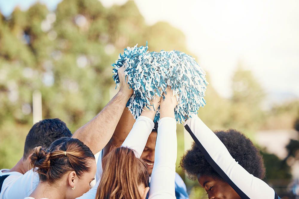 A group of cheerleaders are holding pom poms in their hands in a huddle.