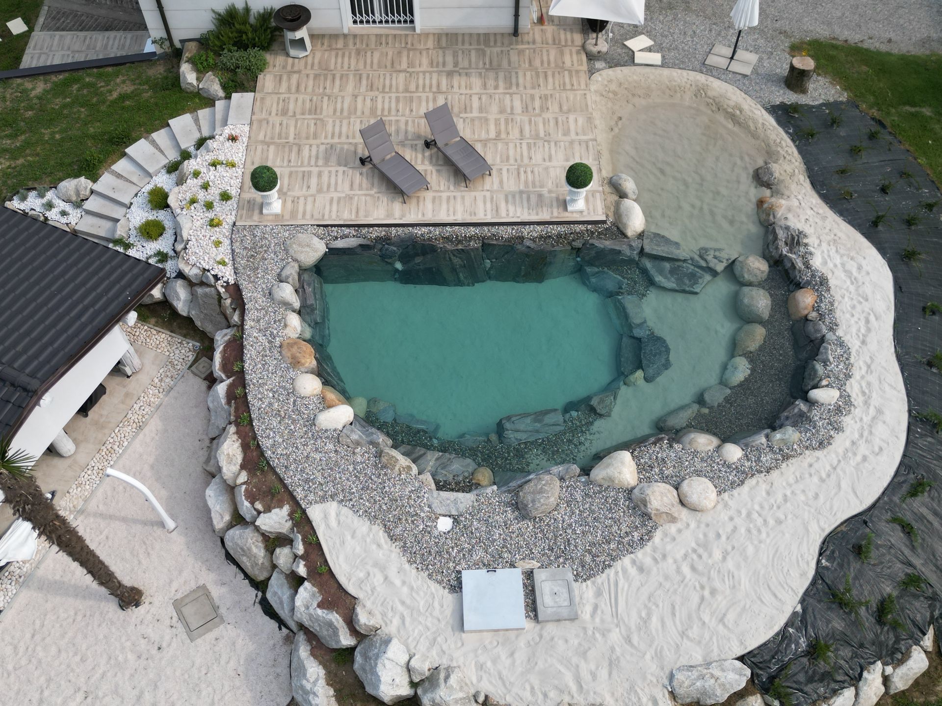 piscina naturale modello Caraibi con sabbia e rocce di Rocks Design