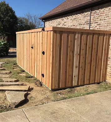 A wooden fence is sitting next to a brick building.