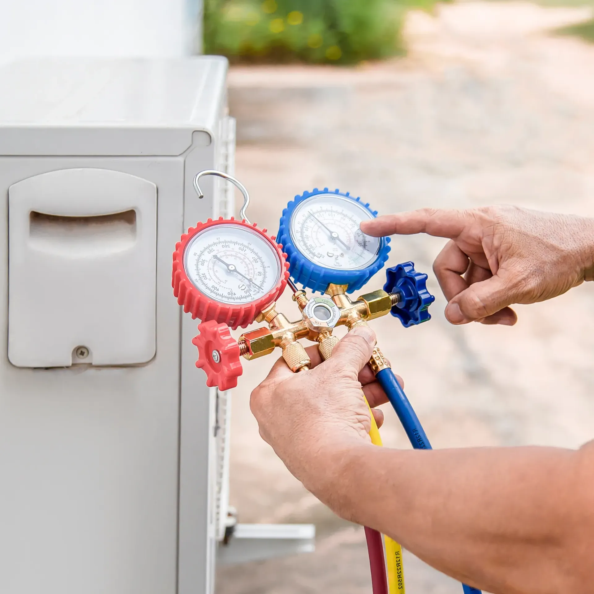 Finnegan’s Heating Air Conditioning - A person is using a gauge to check the pressure of an air conditioner.