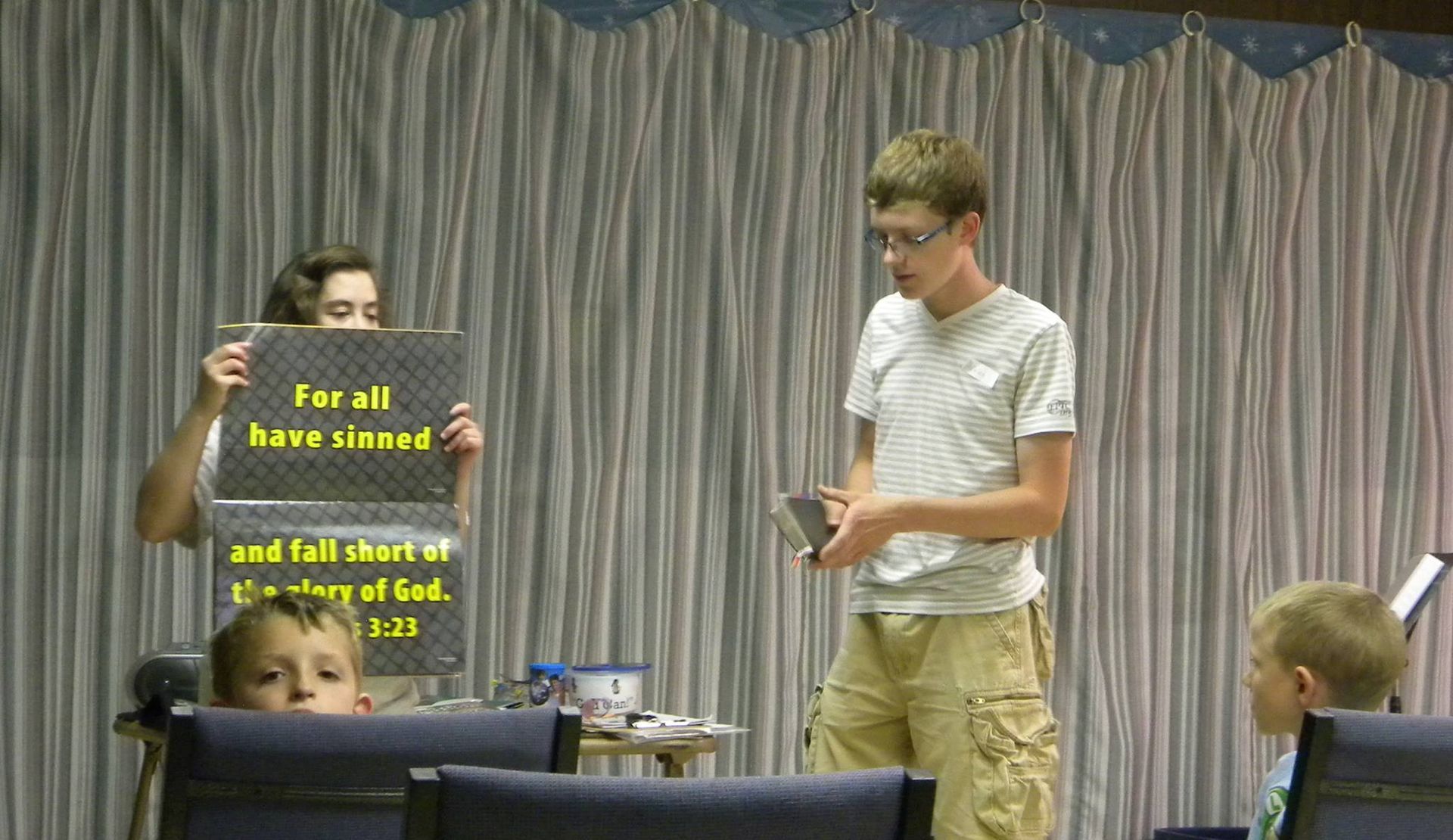 People in a room presenting a sign that reads 