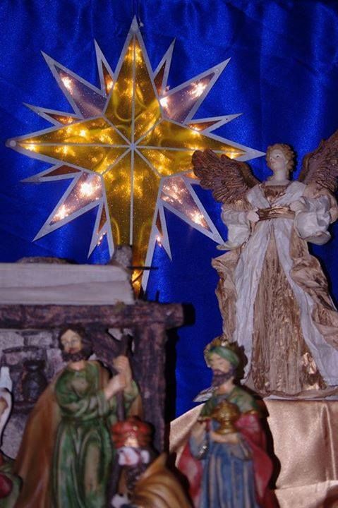 Christmas nativity scene with illuminated star, angel, and figures in front of a blue backdrop.
