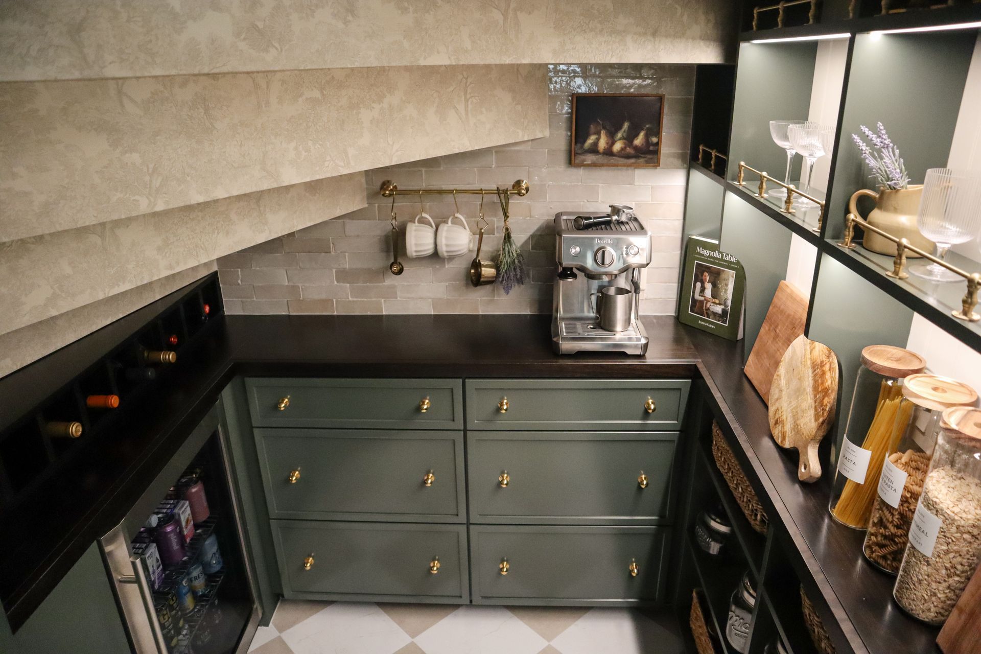 Green pantry with drawers, countertop, espresso machine, wine rack, and shelves.