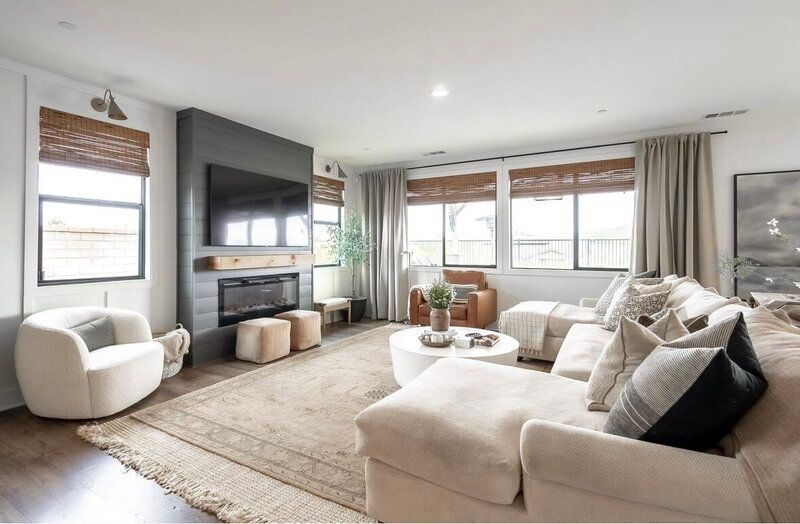 Living room with sectional sofa, fireplace, neutral decor, and large windows.