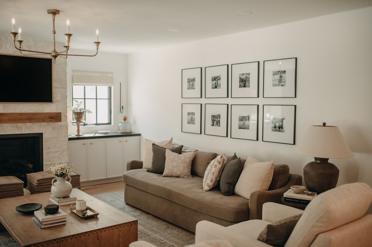 Living room with a fireplace, sofa, gallery wall, and a chandelier.