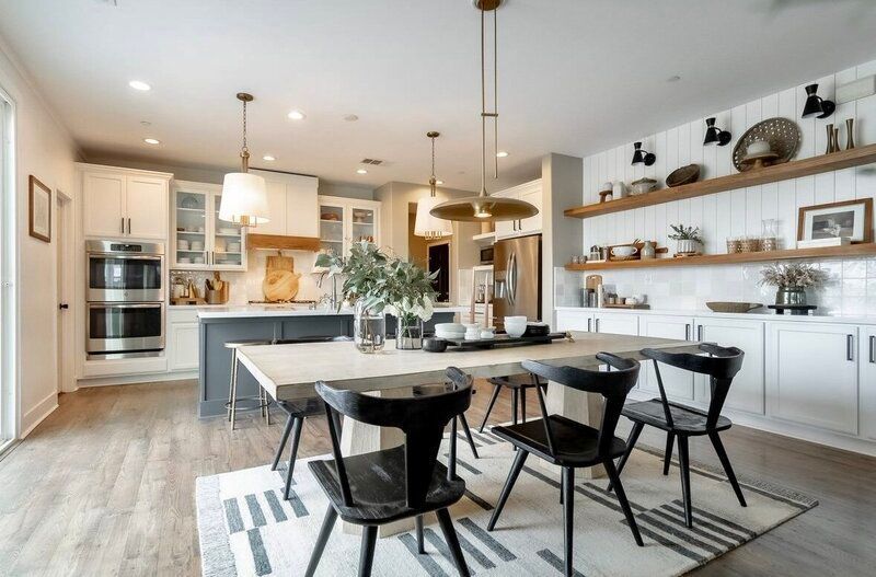 Modern kitchen and dining room: light wood floor, white cabinets, black chairs, open shelves.