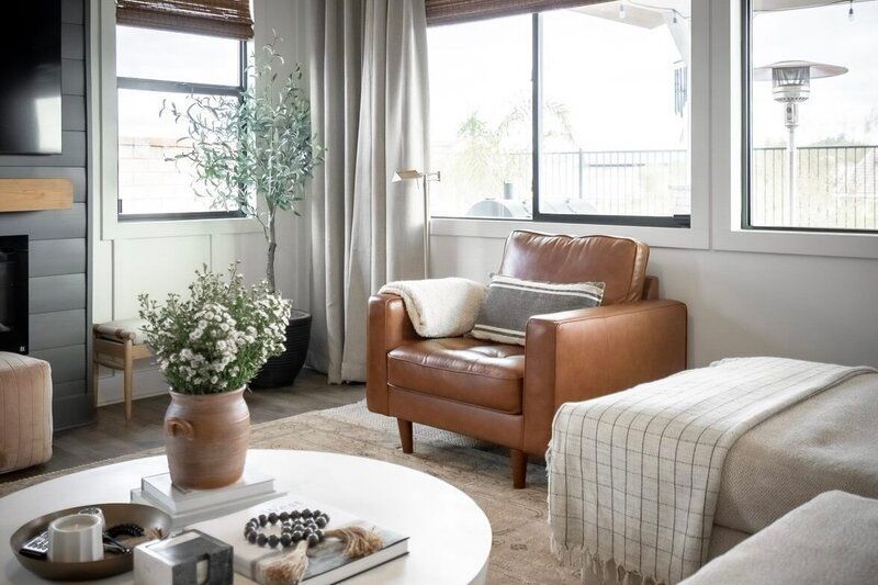 Cozy living room with a leather armchair, round coffee table, and large windows.