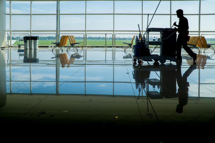 a silhouette of a man cleaning a floor in an airport