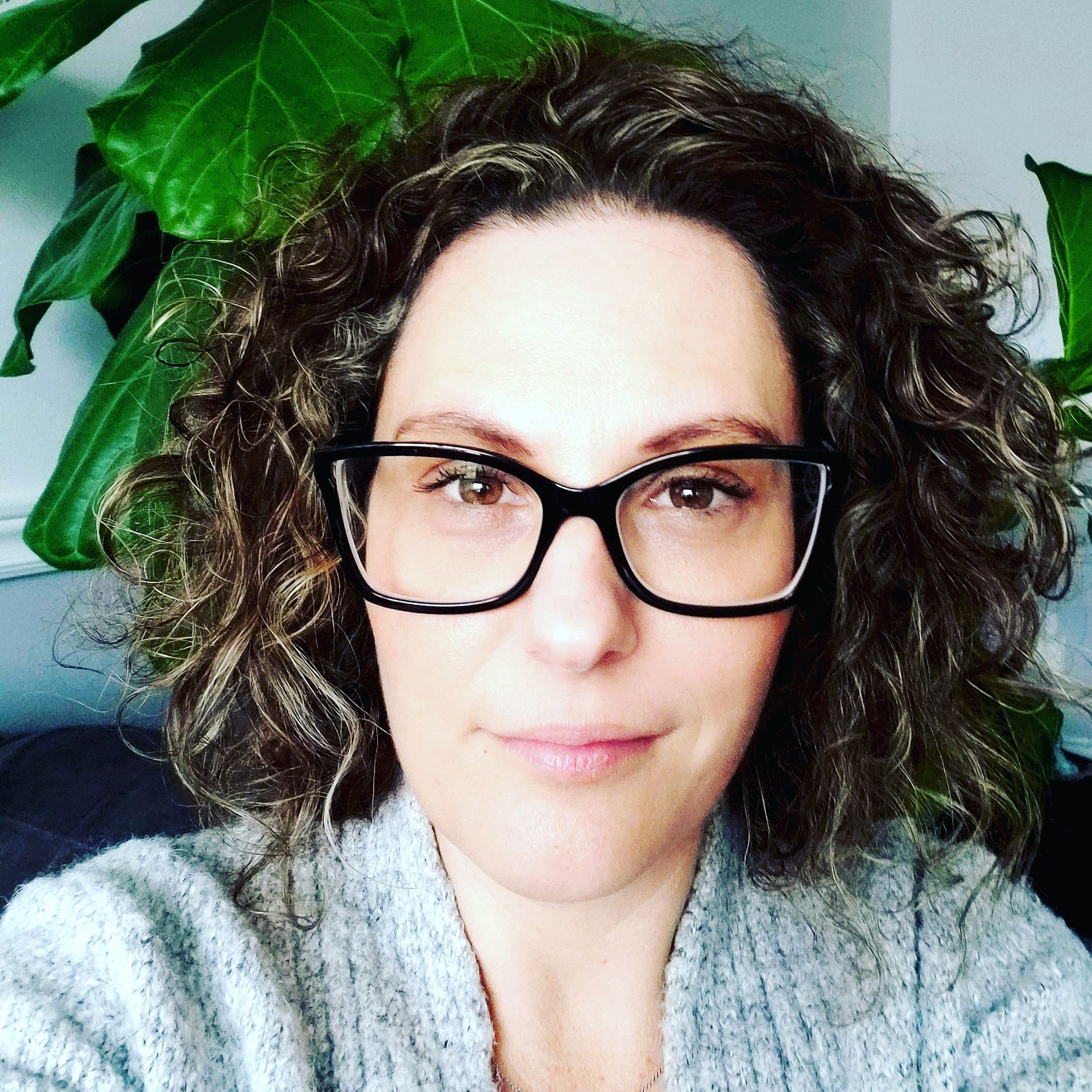 A woman wearing glasses and a scarf is smiling for the camera.