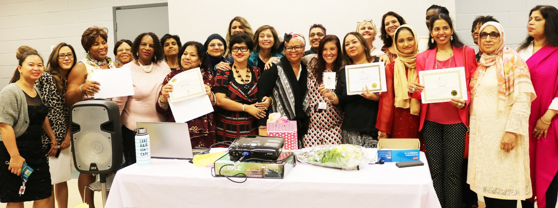 a group of women are standing around a table holding certificates .