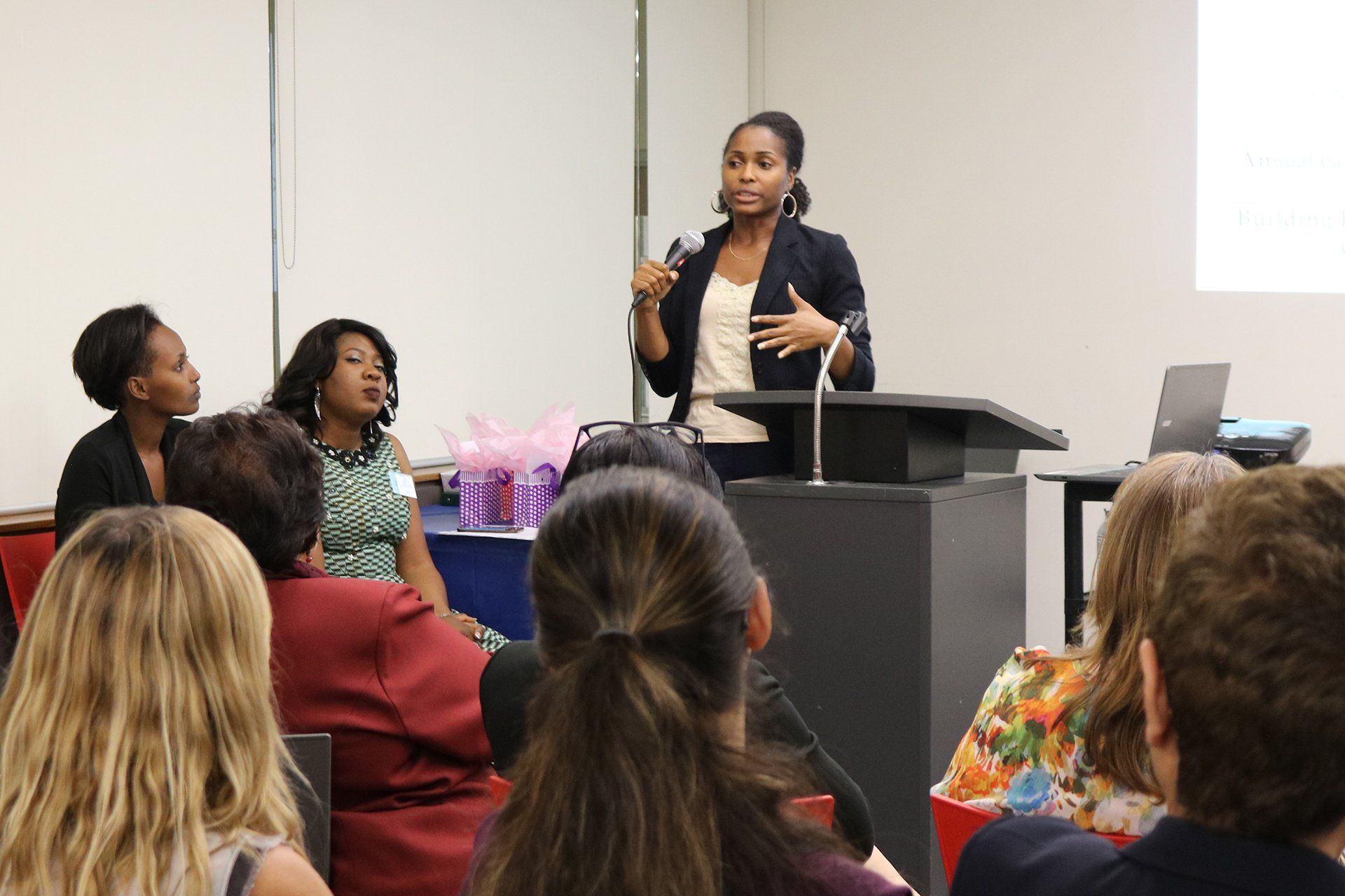 A woman is standing at a podium giving a presentation to a group of people.