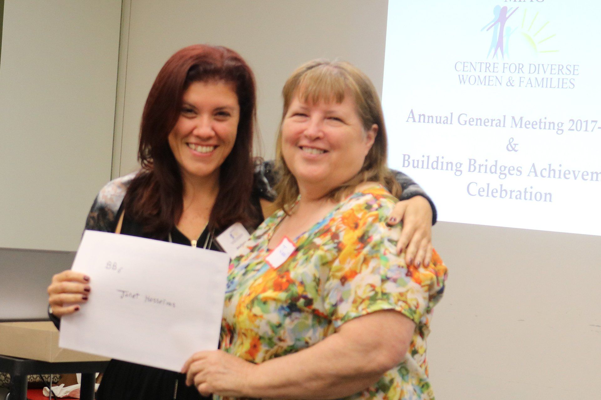 Two women are posing for a picture and one is holding a certificate.