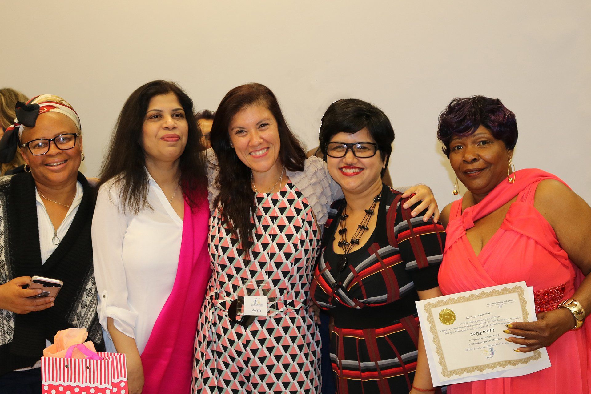 A group of women posing for a picture with one woman holding a certificate