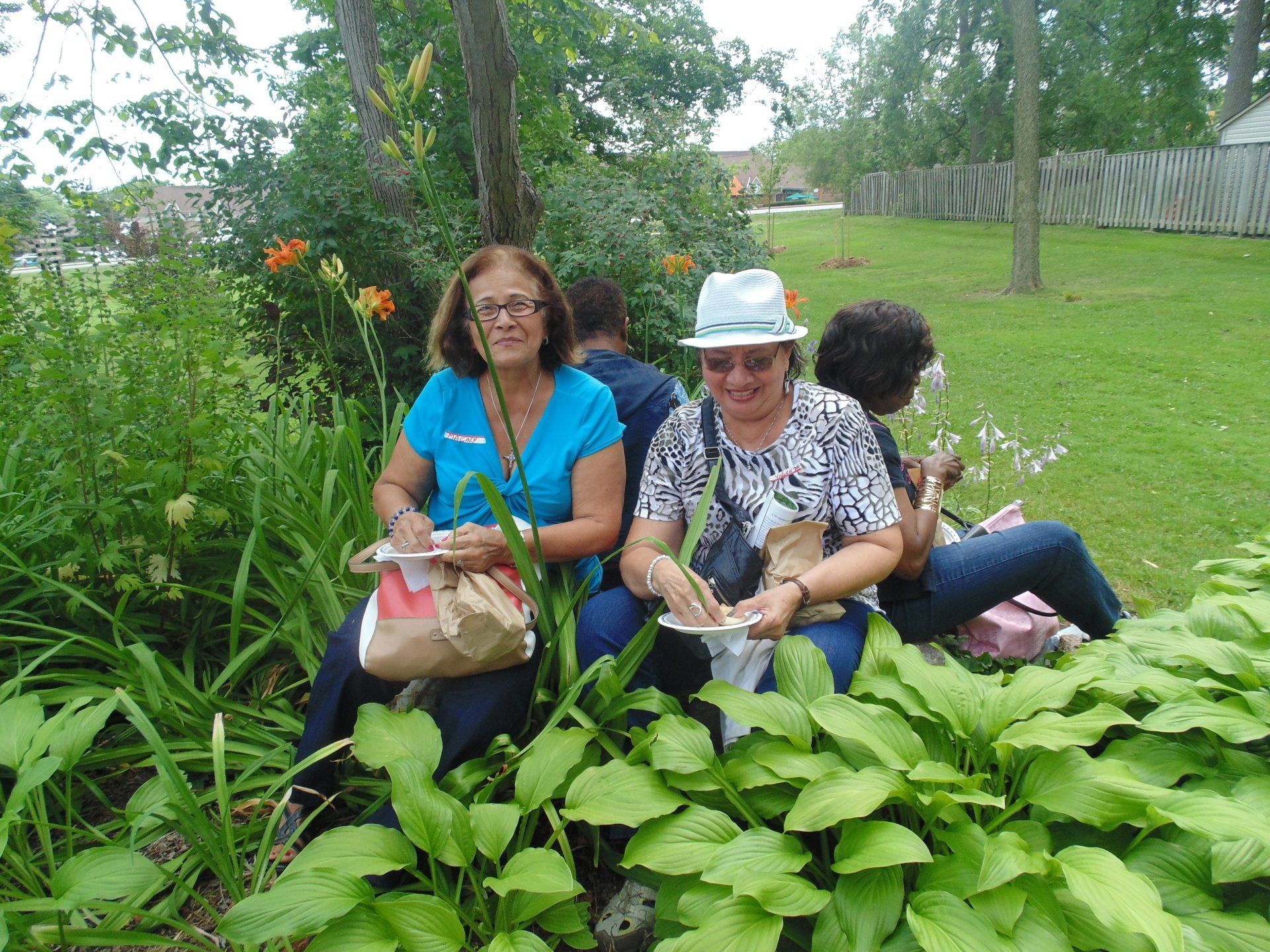 A group of women are sitting in a park surrounded by plants.