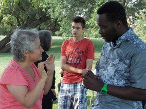 A group of people are standing in a park and one of them is wearing a shirt that says focus