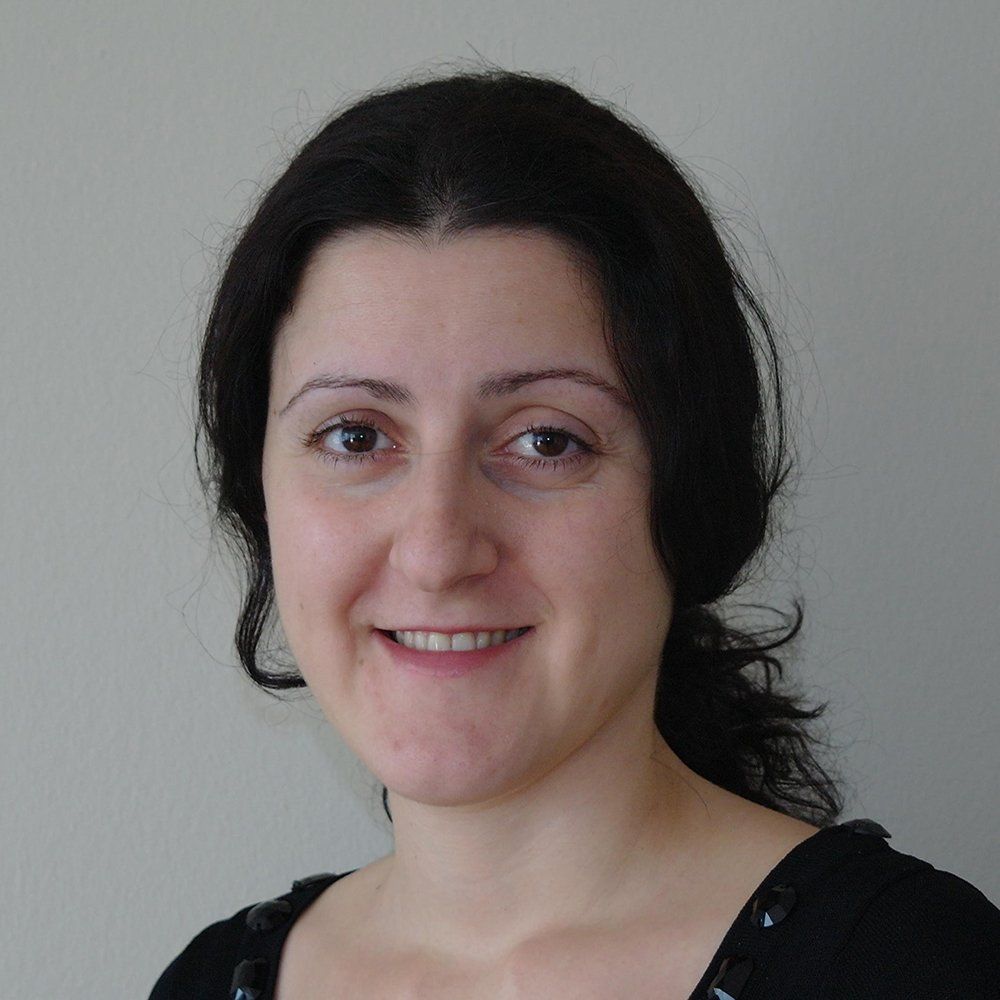 A woman with dark hair is smiling and wearing a black shirt