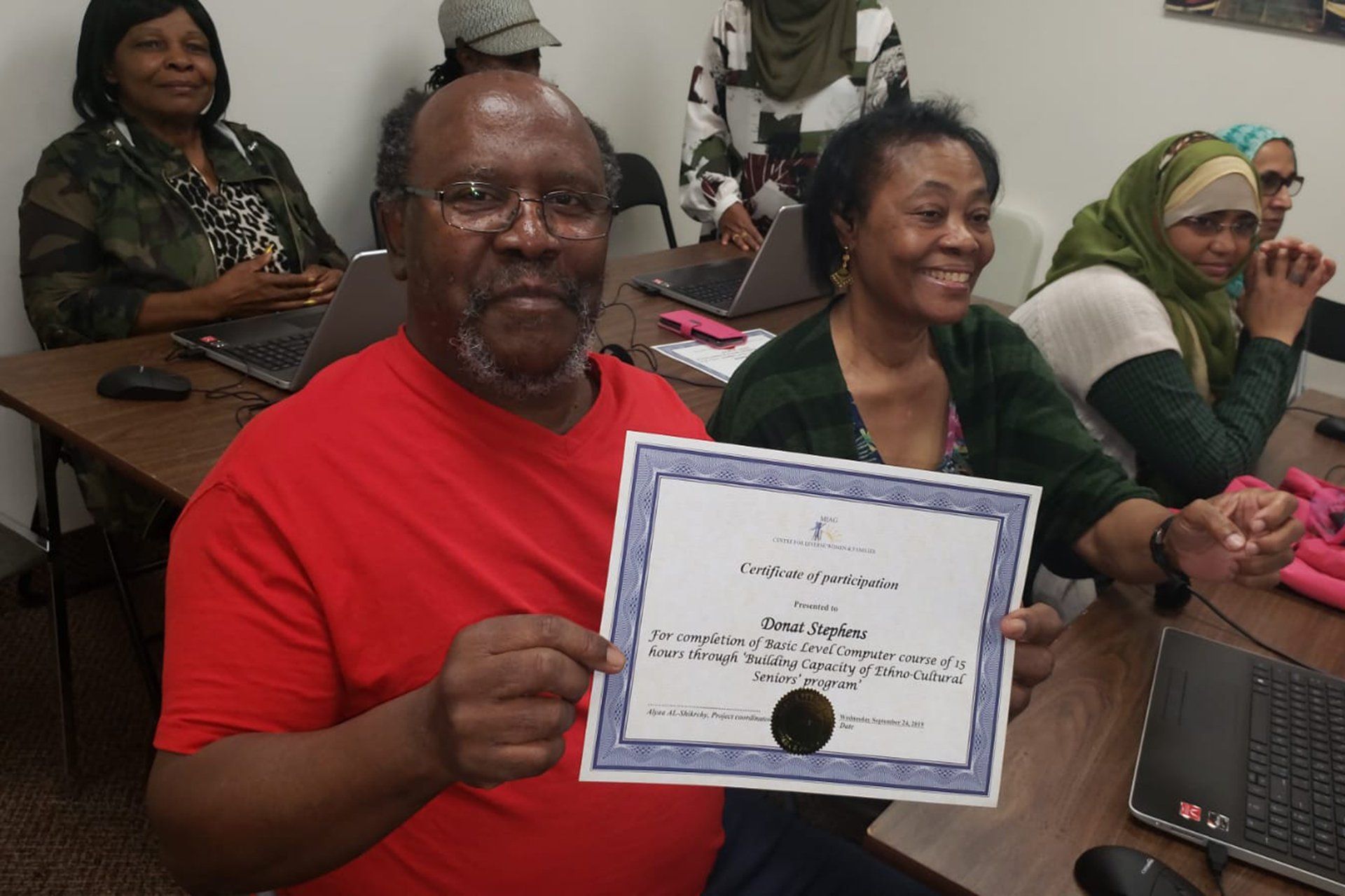 A man in a red shirt is holding a certificate