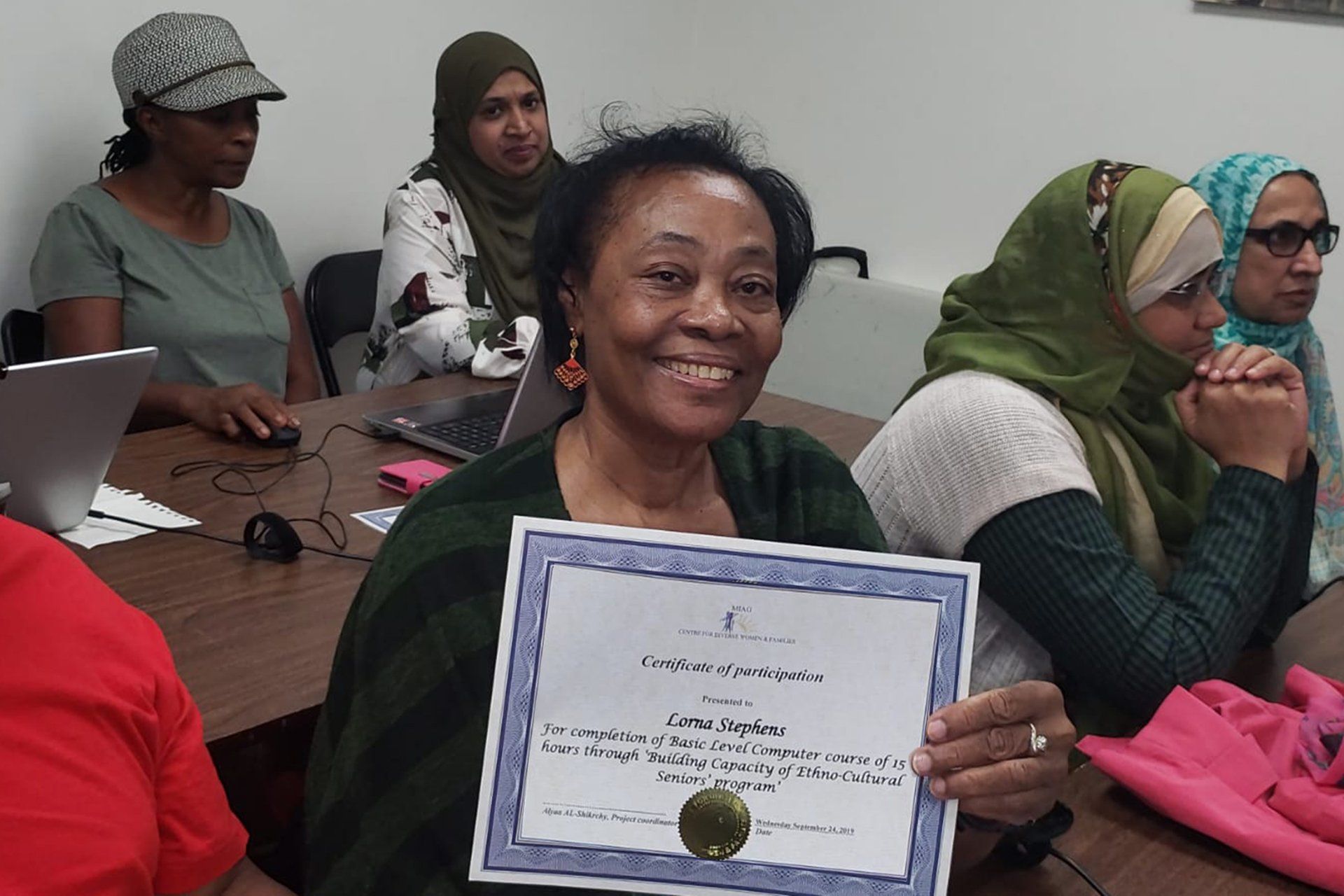 A woman is holding a certificate in front of a group of people