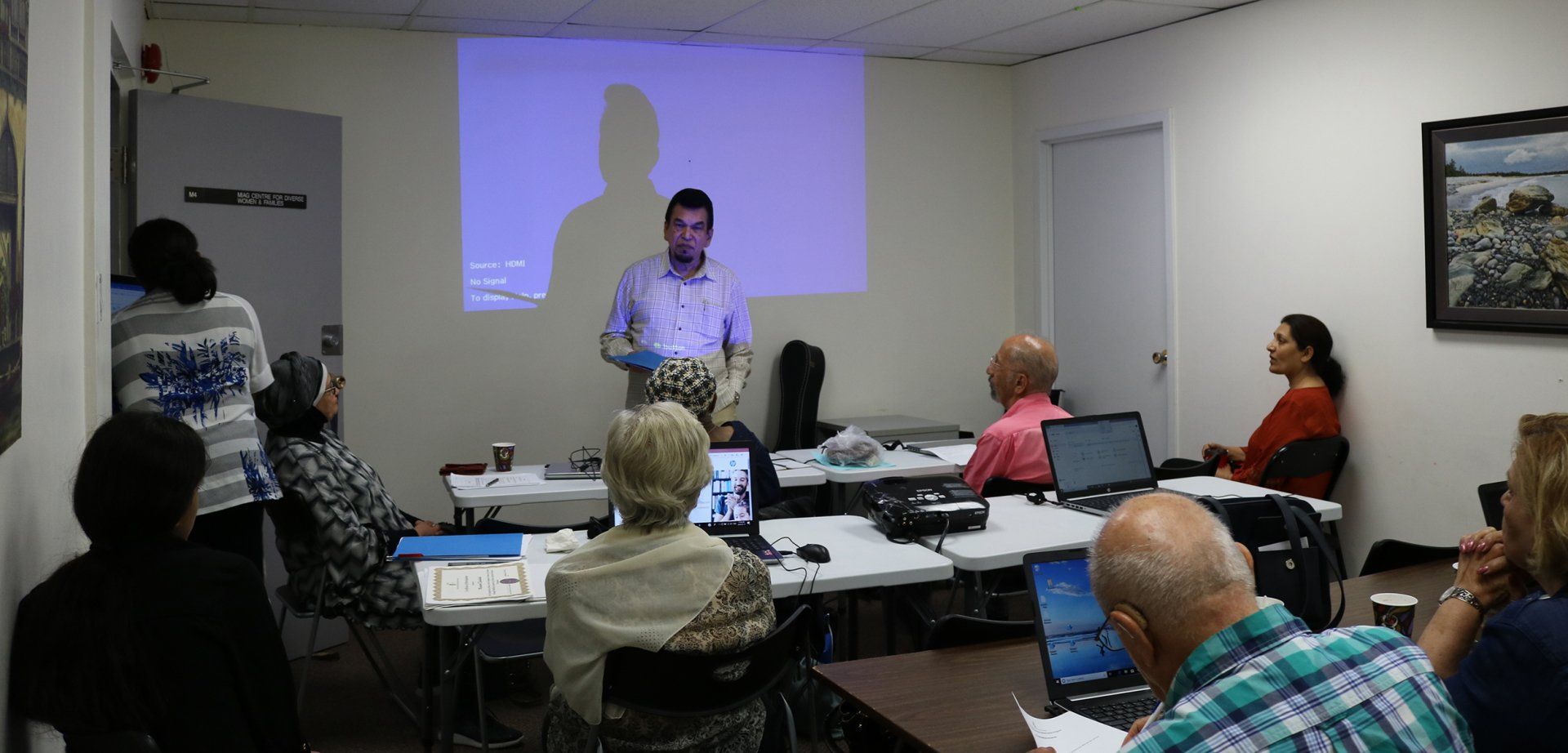 A man is giving a presentation to a group of people in a classroom.