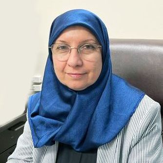 A woman wearing a blue hijab and glasses is sitting in a chair.