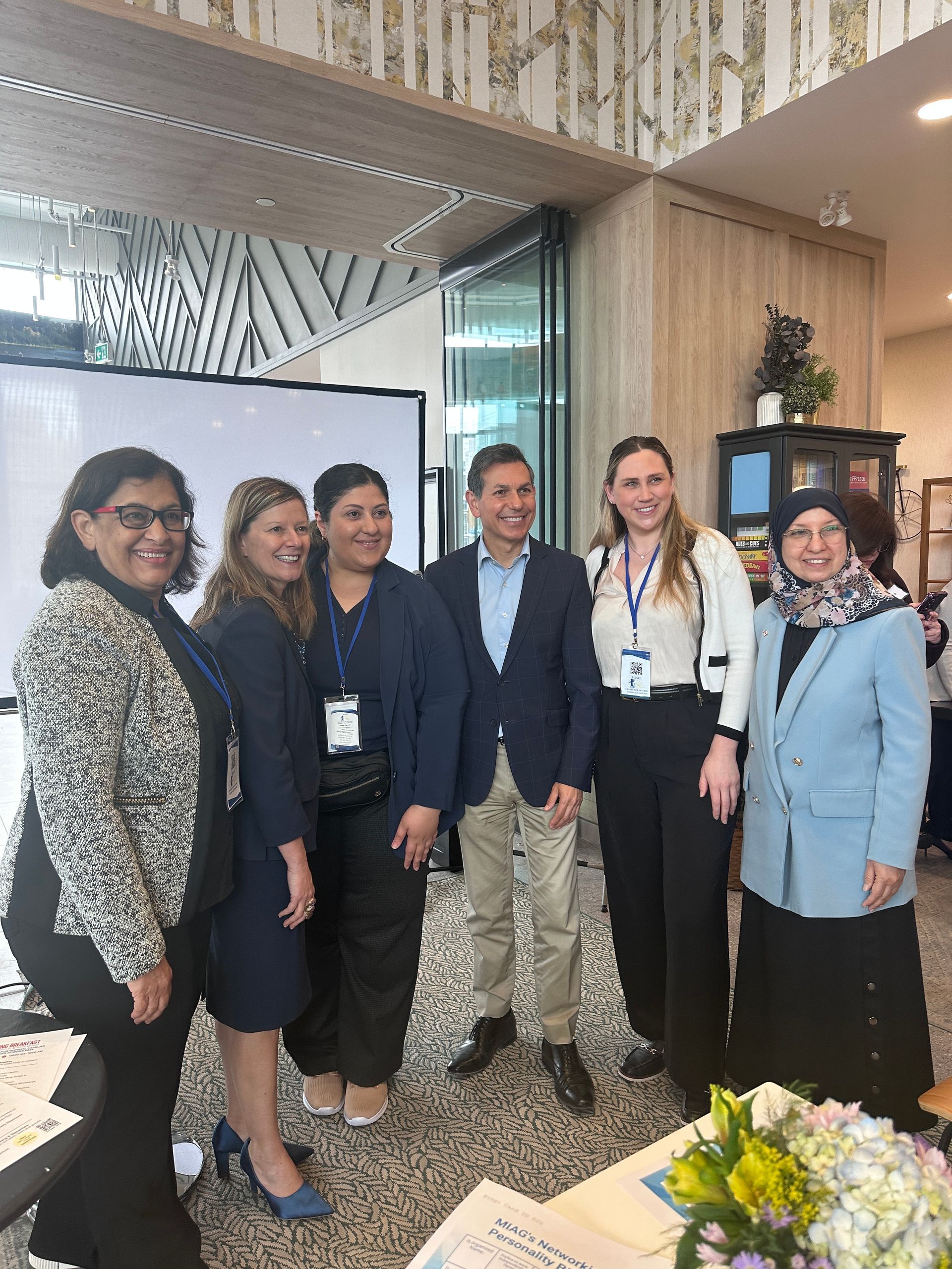 Group of six people smiling for a photo indoors, possibly at an event.