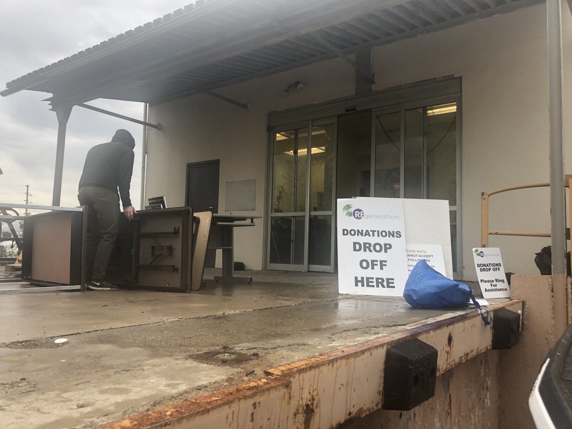 A man is standing in front of a building with a sign that says `` drop off here ''.