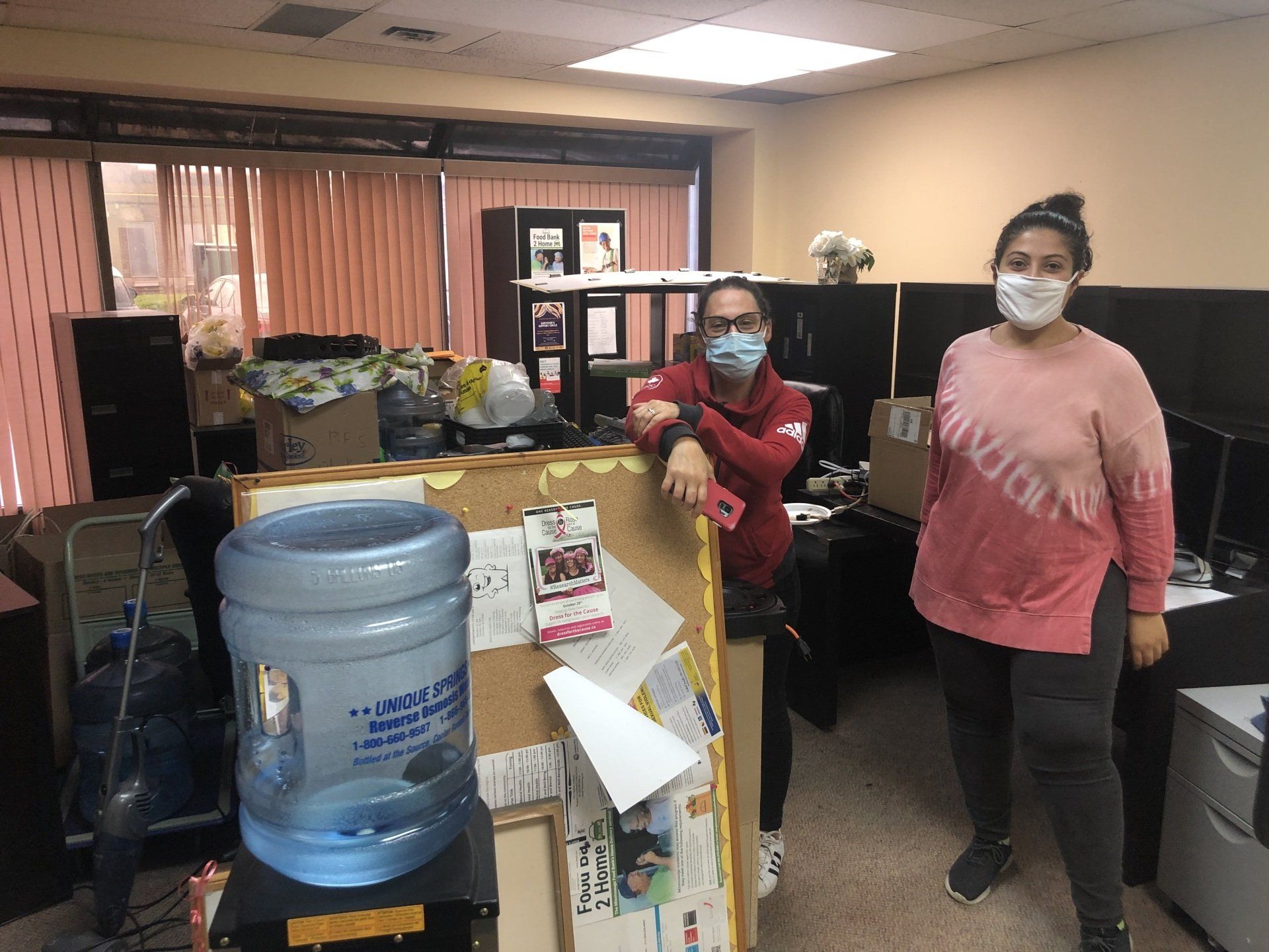 A man and a woman wearing face masks are standing in an office.