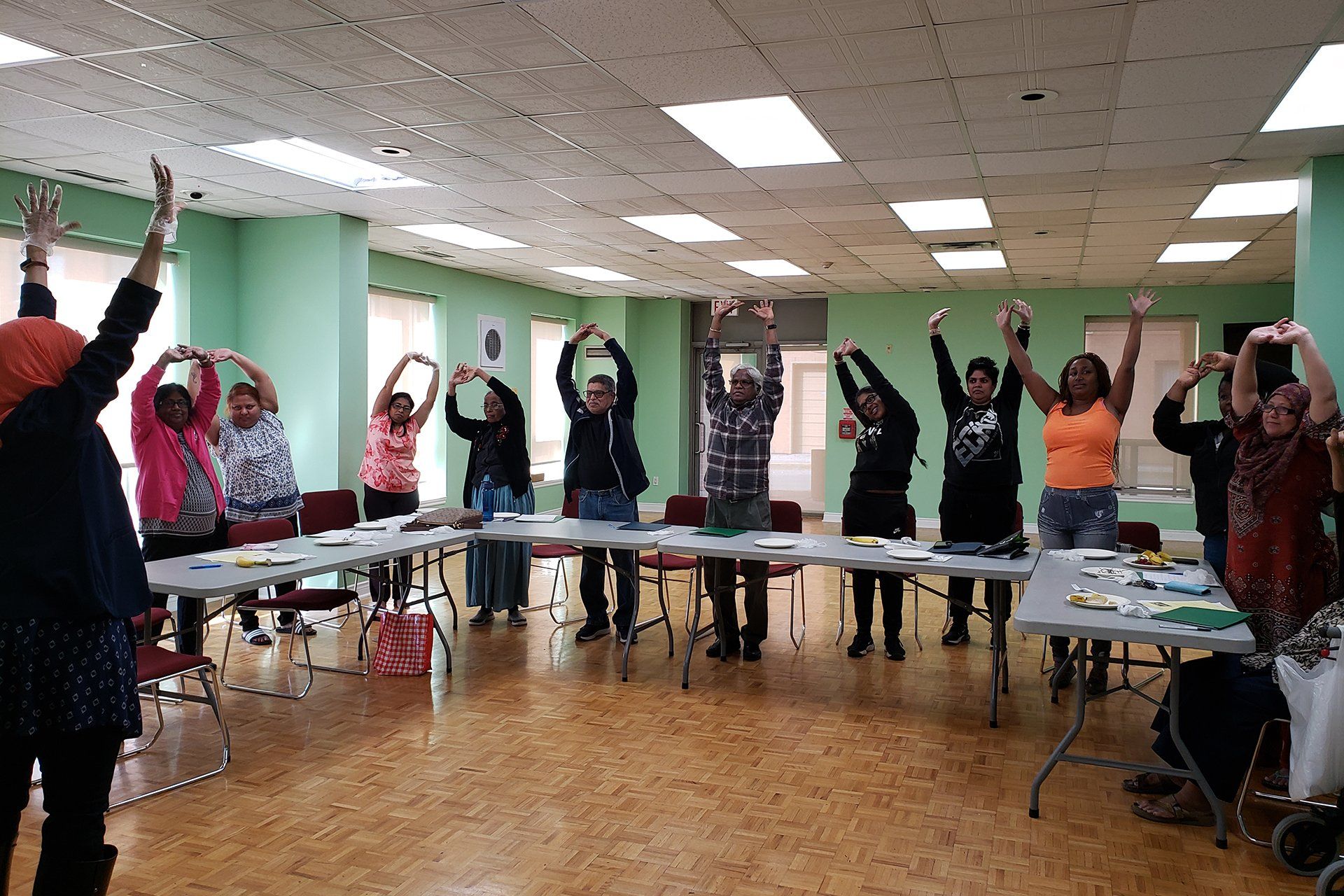 A group of people are stretching their arms in a room.