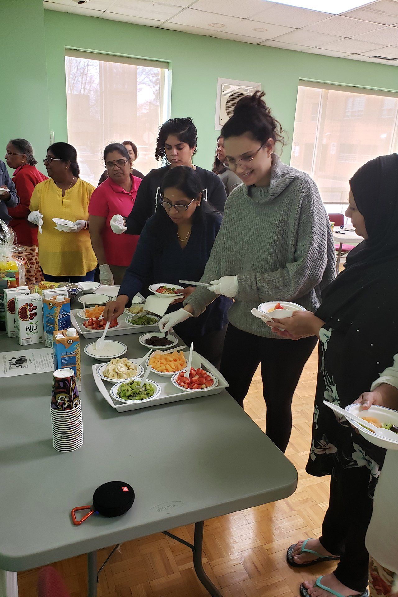 A group of women are standing around a table eating food.