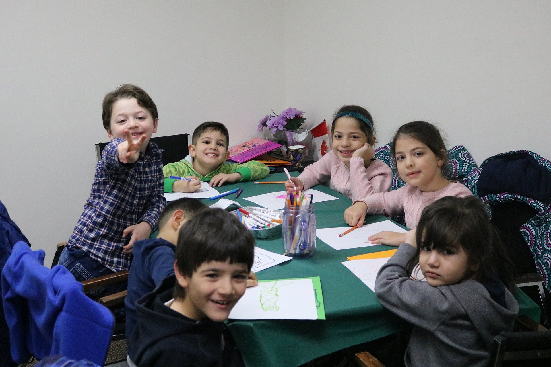 A group of children are sitting at a table with papers on it.