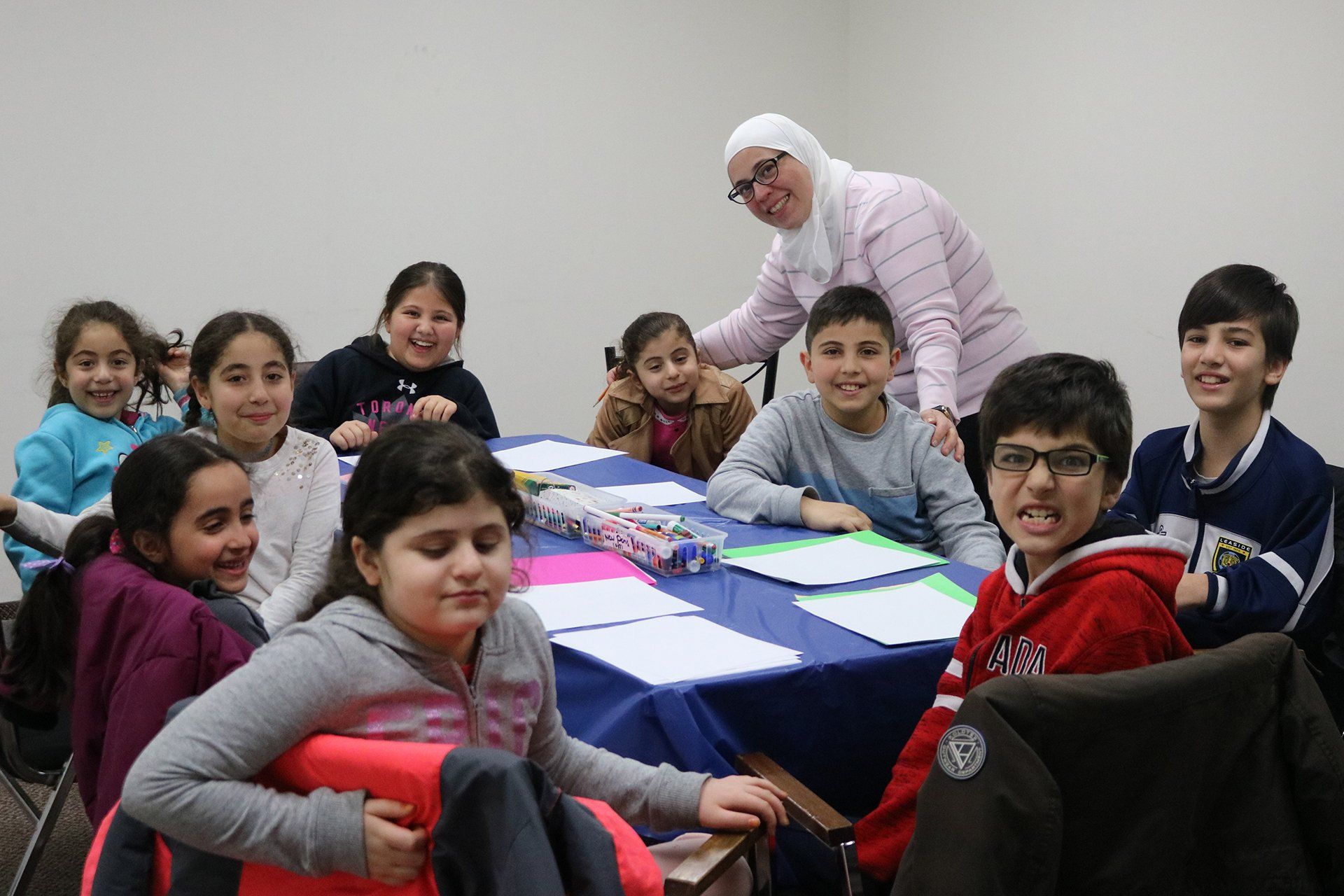A group of children are sitting around a table with their teacher.