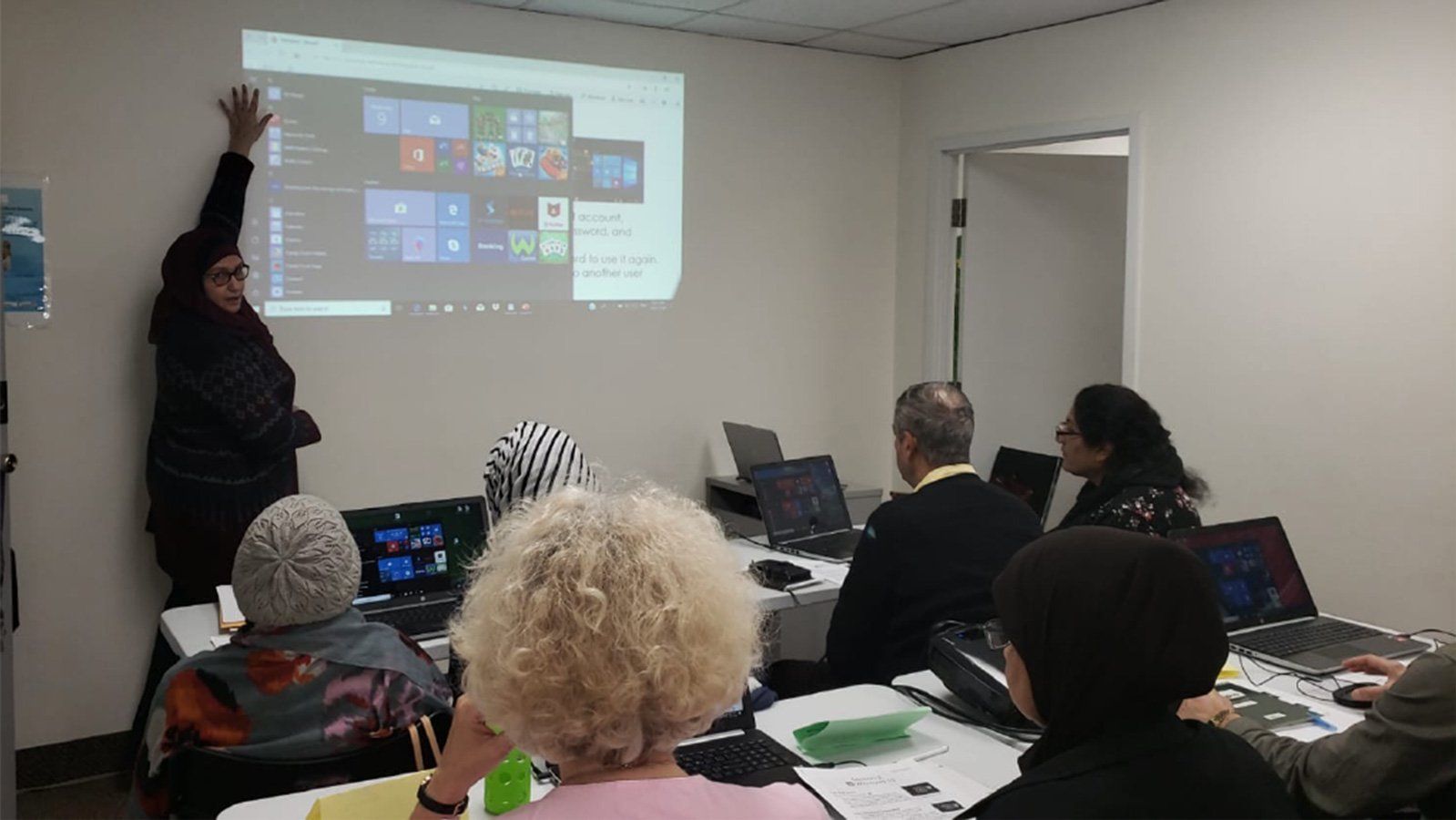 A woman is giving a presentation to a group of people in a room.