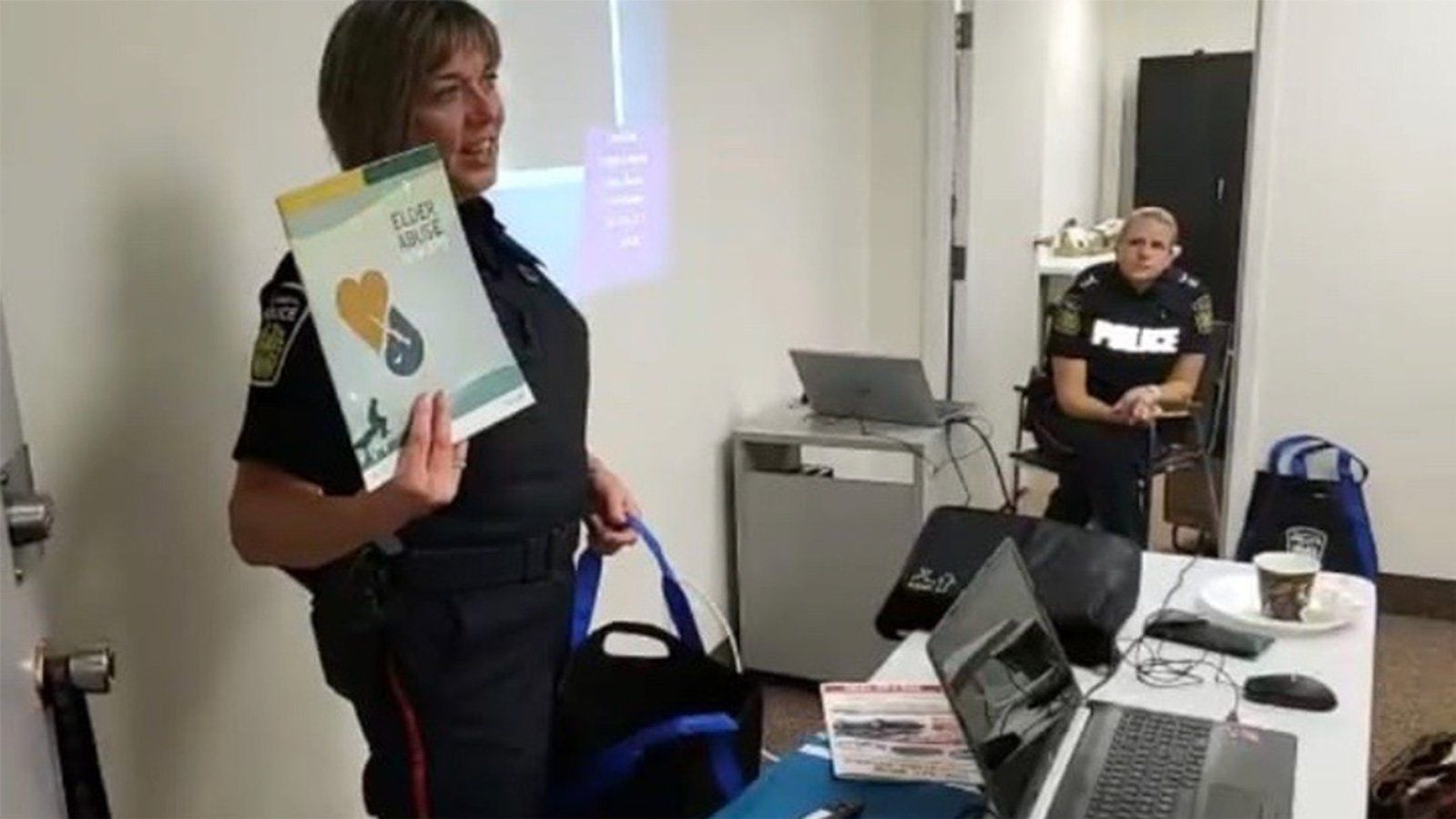 A police officer is holding a book in front of a group of people.