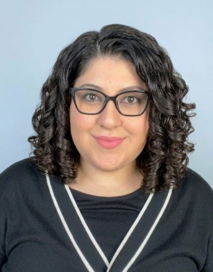 A woman wearing a plaid shirt is smiling for the camera