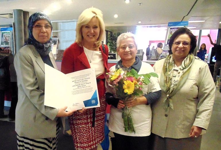 A woman in a red jacket is holding a certificate