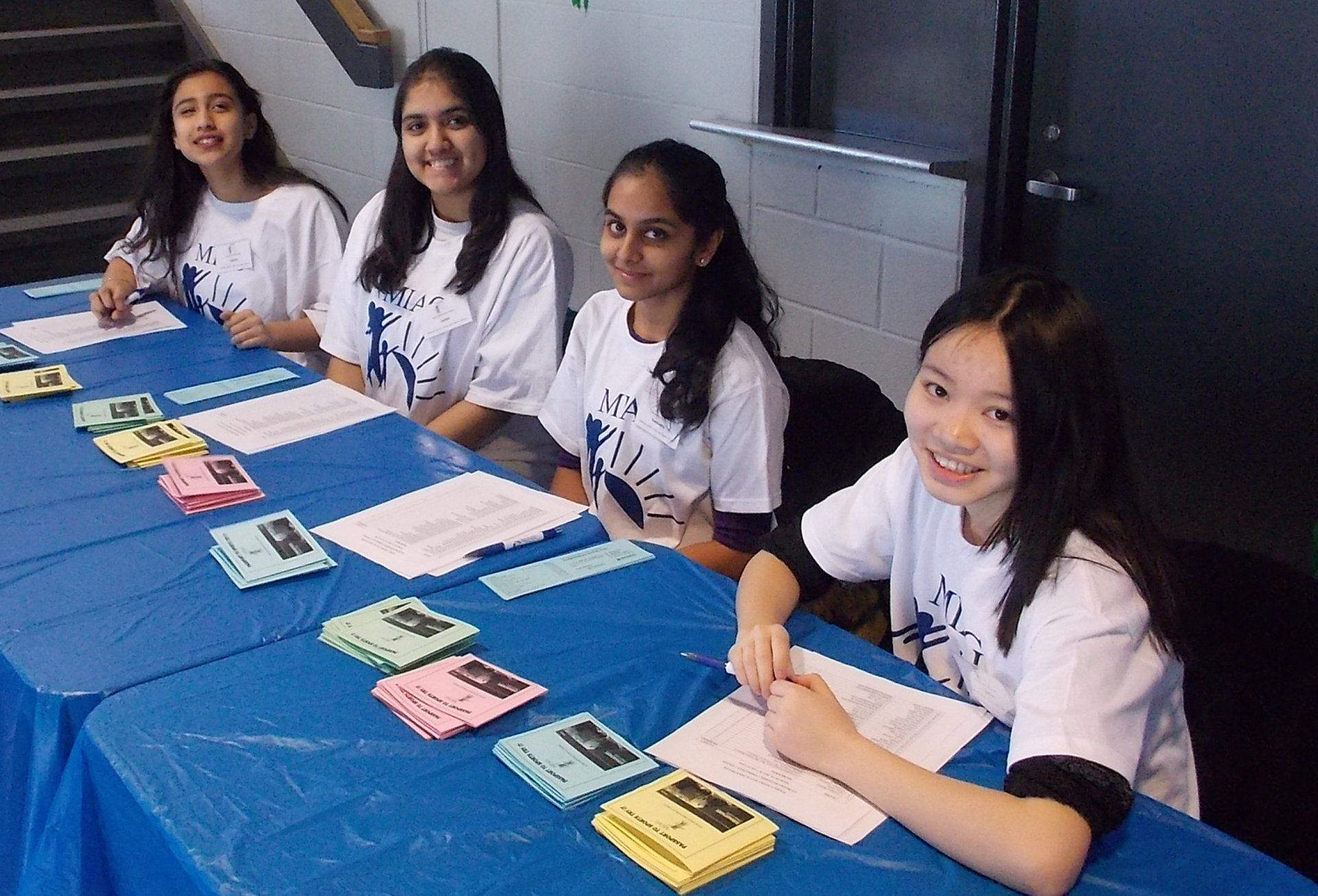 A group of girls are sitting at a table with papers on it