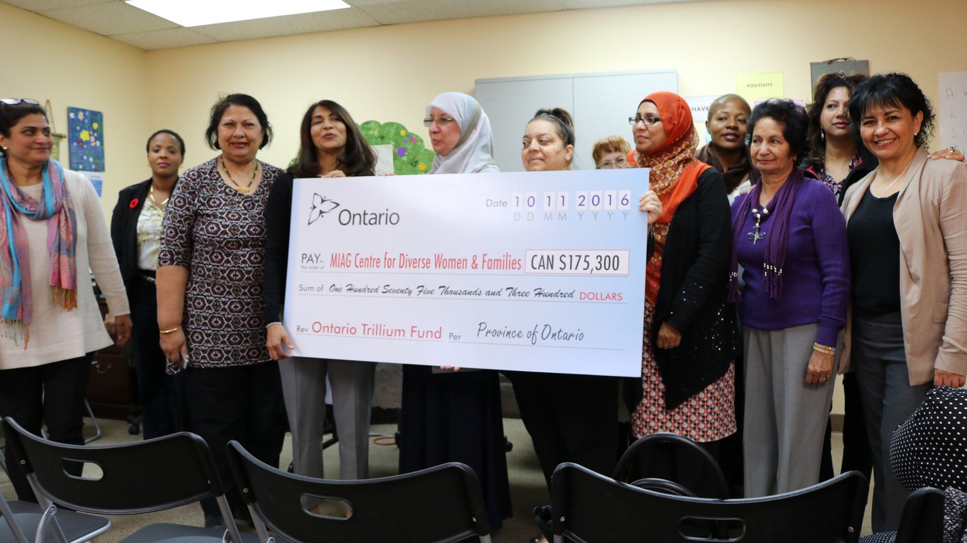 A group of women are posing for a picture while holding a large check.